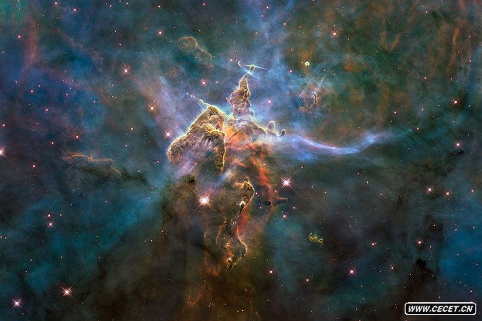 “船底星座”星云 图中所示的柱体,是由气体和尘埃构成的,位于一个汹涌的恒星育儿室:船底座星云。这张照片显示的是3光年长的柱体的顶端,沐浴在炽热的大恒星的光芒下。这些大恒星位于这张图片上部以外的区域。来自这些大恒星炽热的辐射和高速风(带电粒子流)正在雕刻这一柱体,并导致柱体内部形成新恒星。可以看到这一结构的上部发射出气体和尘埃流。